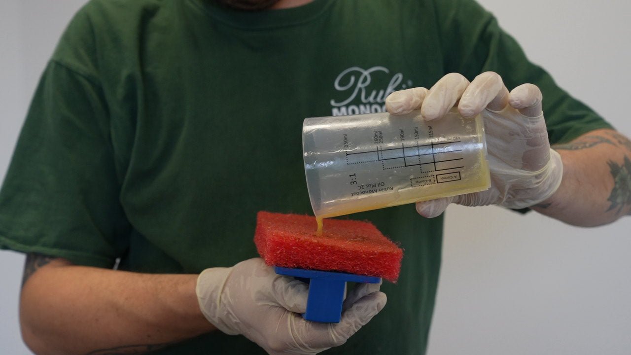 Person adding Rubio Monocoat Wood Oil to a red application pad.
